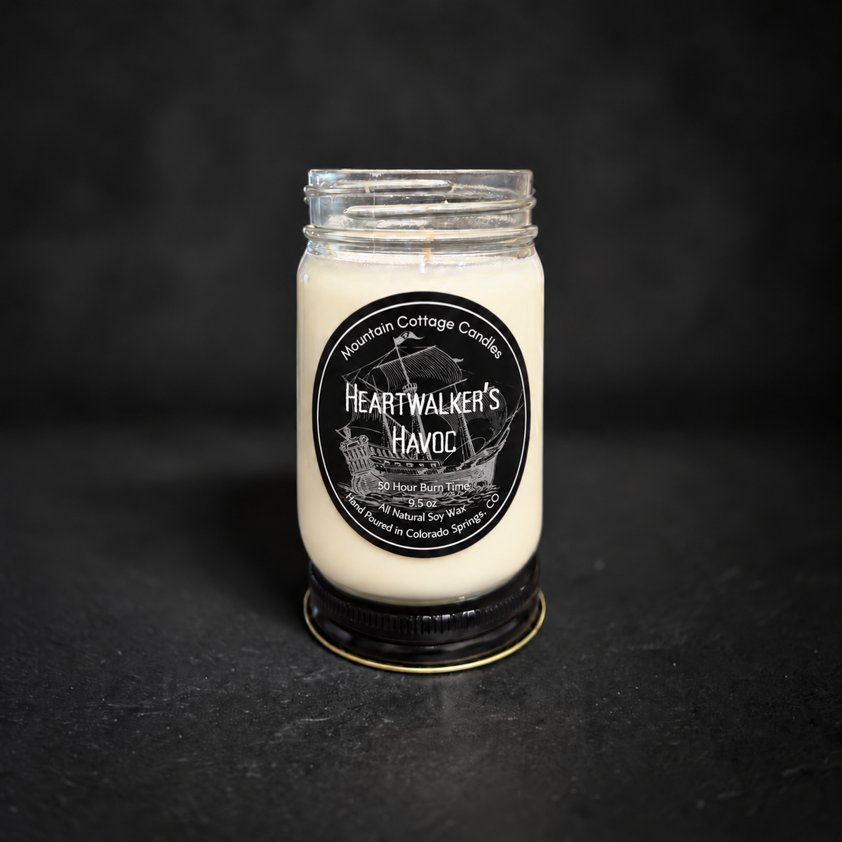 Heartwalker's Havoc soy candle in a clear glass jar with a black lid, black label with a tall ship under full sail