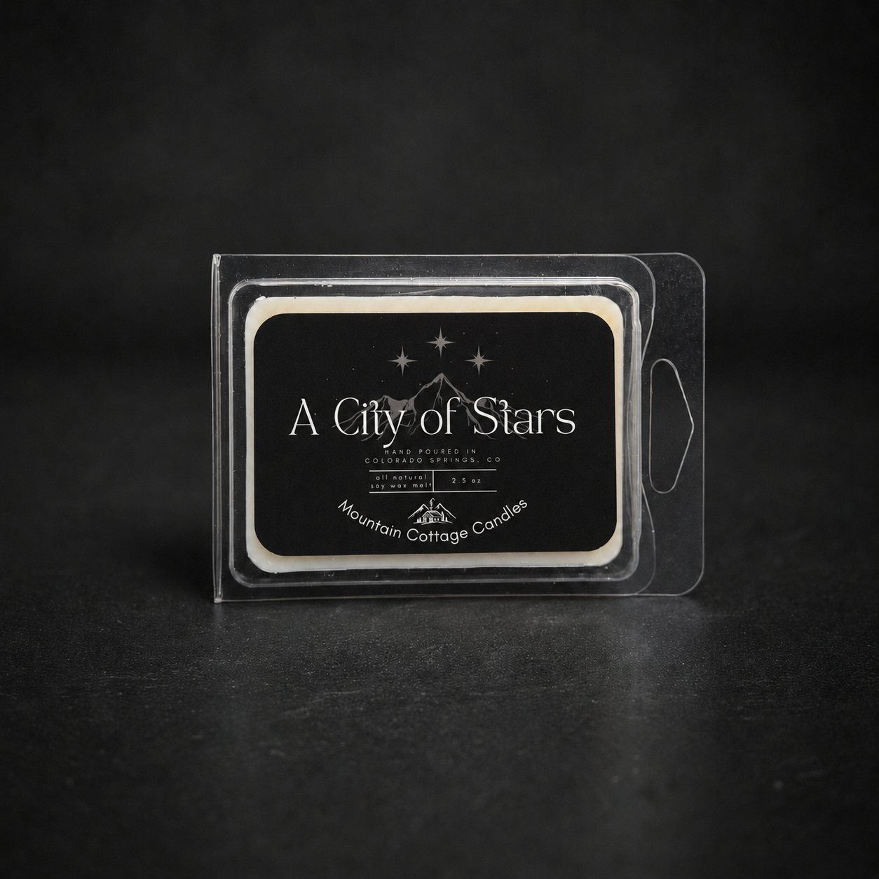 A City of Stars soy wax melt in a clear clamshell pack, black label showing a mountain range beneath a starry sky
