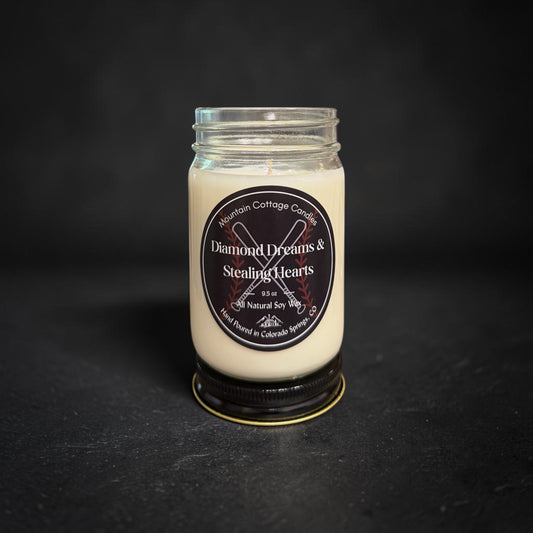 Diamond Dreams & Stealing Hearts soy candle in a clear glass jar with a black lid, black label showing crossed baseball bats