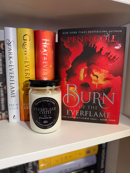 Everflame Oath soy candle on a white shelf in front of Penn Cole's Kindred's Curse Saga, Burn of the Everflame standing face out