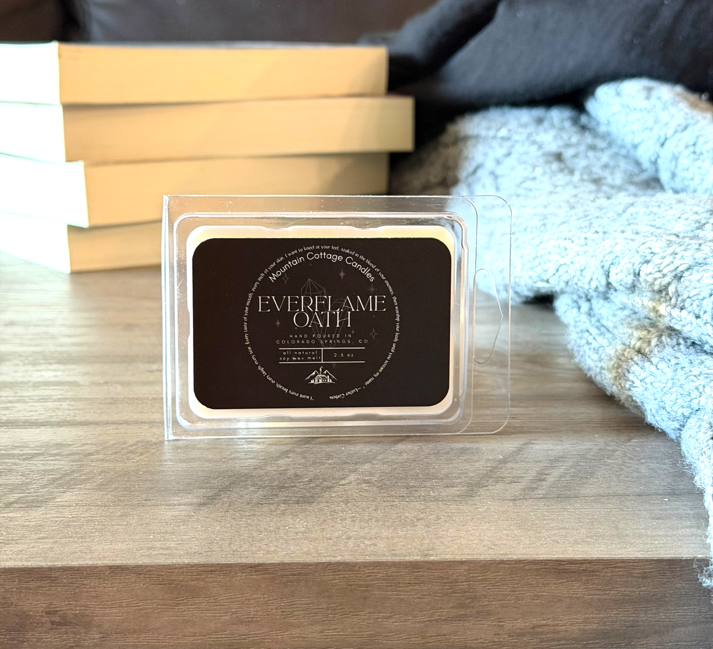 Everflame Oath 2.5 oz soy wax melt on a wood table beside a stack of books and a folded knit sweater