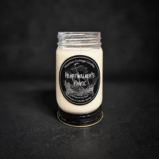 Heartwalker's Havoc soy candle in a clear glass jar with a black lid, black label with a tall ship under full sail
