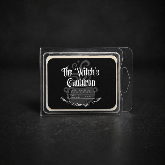 The Witch's Cauldron soy wax melt in a clear clamshell pack, black label with ornate scrollwork and sparkles